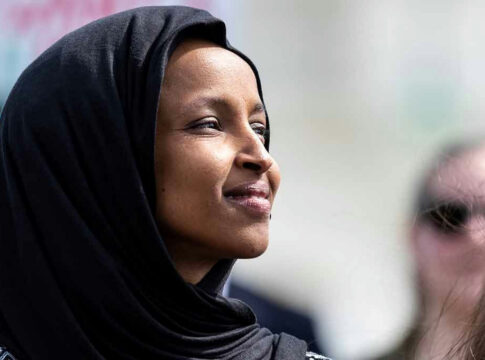 A woman wearing a black hijab looking thoughtfully into the distance