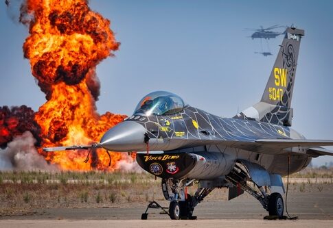 F-16 fighter jet on the ground with an explosion in the background