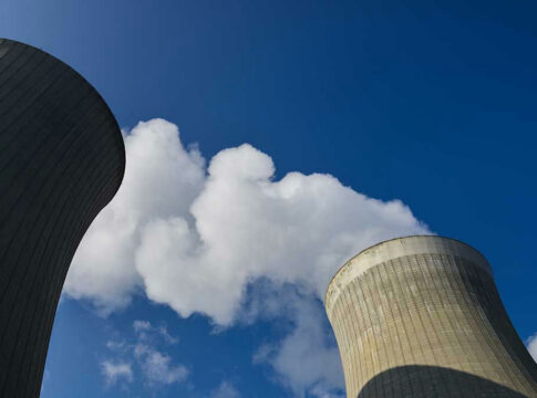 Cooling towers emitting steam under a clear blue sky.