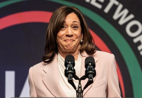Female speaker smiling at a podium with microphones